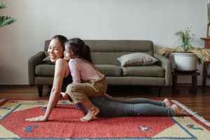 Family Role Play: Overall Fitness .Photo of girl hugging her mom while doing yoga pose