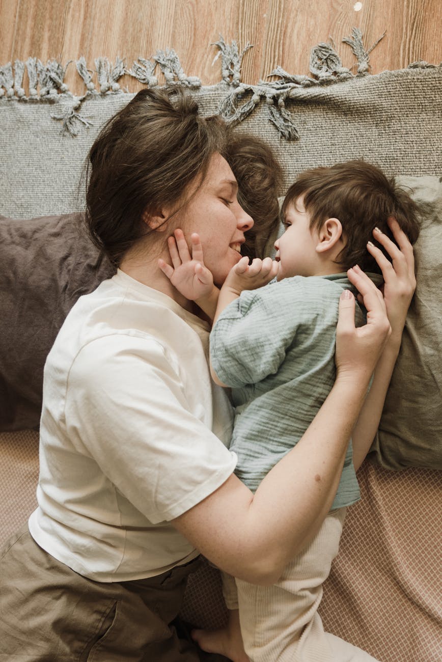 happy young mother embracing adorable toddler, trying to sleep